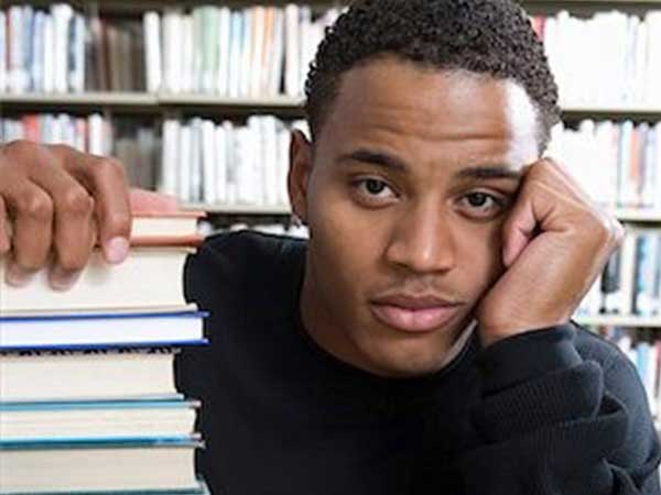 Student gazing next to a stack of books