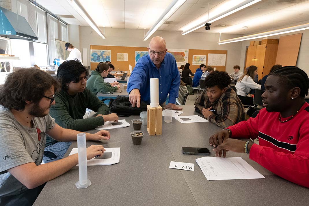 Teacher showing a group of students a beaker