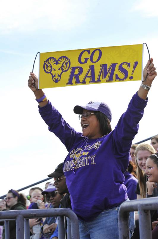 Homecoming event photo - student at a homecoming event with West Chester University sweatshirt and WCU hat holding up a sign with the Ram logo and the words Go Rams!