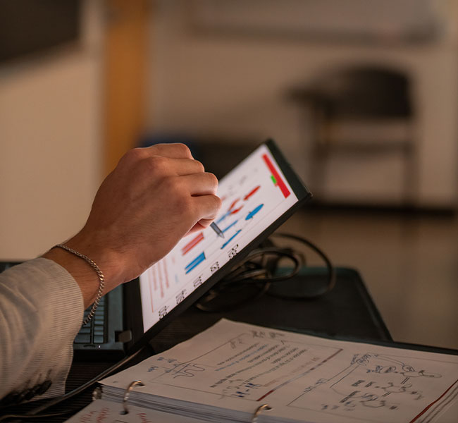 A student working on their tablet, only their hand is showing
