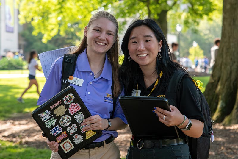 2 student workers at orientation smiling and wearing WCU polos