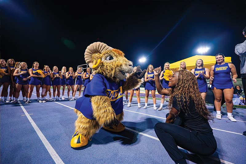 Rammy and a WCU dance team student dancing in a circle of WCU cheerleaders and WCU dance team
