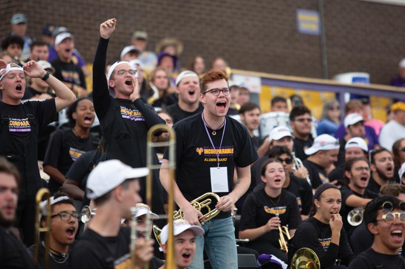 the marching band in the crowd is cheering while holding their instruments