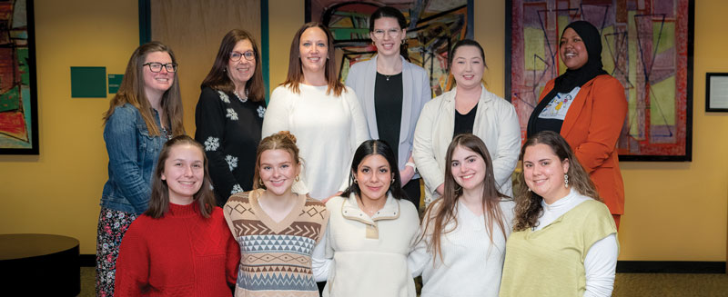 (Top L to R) Mentors Amanda Tingle Oline ’09, Linda Casotti ’86, Courtney Lloyd ’10, M’18, Kristen Loughlin ’21, Alicia Long ’15, M’16, Edwena Lanier ’23, with (Bottom, L to R) students Corey Lane, Holly Liebenberg, Damaris Silva, Sophia Shaloka, Jessica Aniloff.