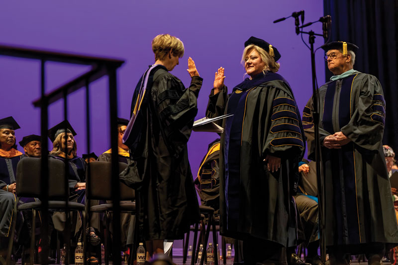 Dr. Cynthia Shapira (L), chair of the Board of Governors for the Pennsylvania State System of Higher Education, administers the presidential oath of office to Dr. Laurie Bernotsky (center), 16th president of West Chester University, at the inauguration celebration on March 28, 2025. Robert M. Tomlinson ’70 (R), chair of WCU’s Council of Trustees, stands ready to present Dr. Bernotsky with the medallion, symbol of the office of the University president.