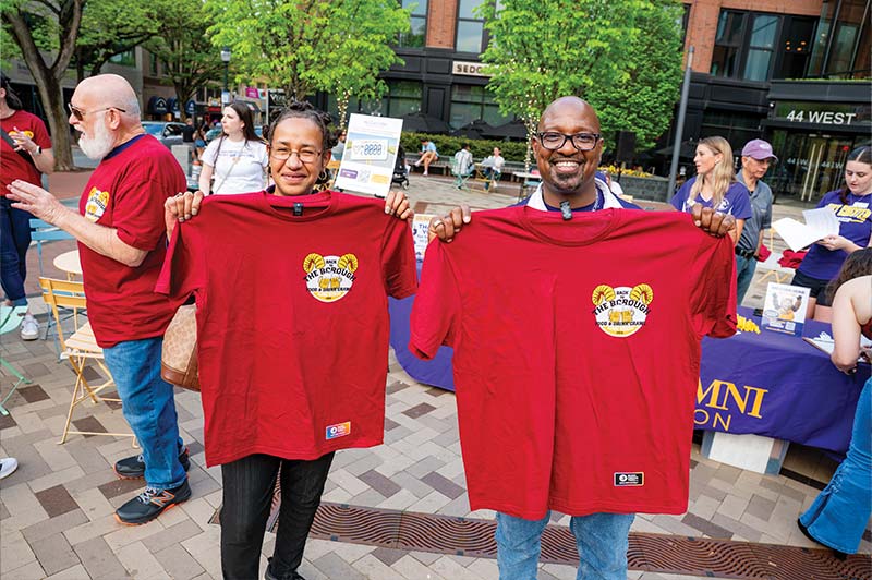 Two people are holding up red event tshirts
