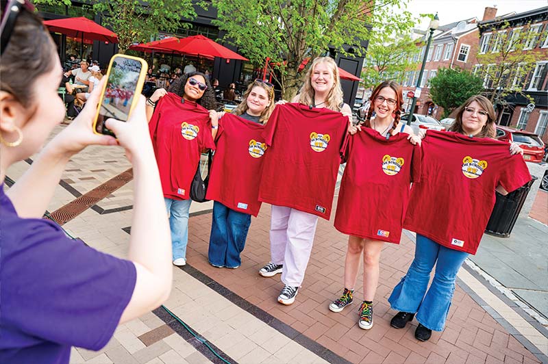 A group of people get their picture taken while holding red event tshirts