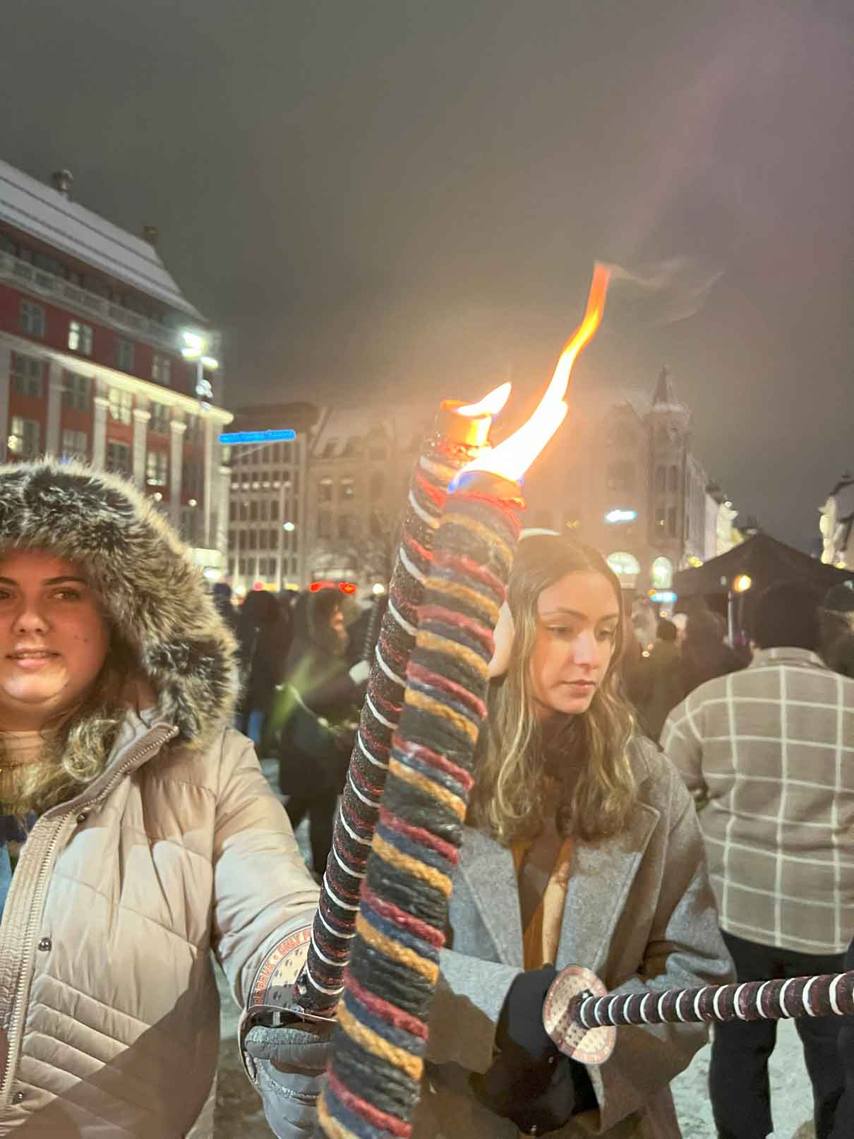 Two people touching candles together by the flame