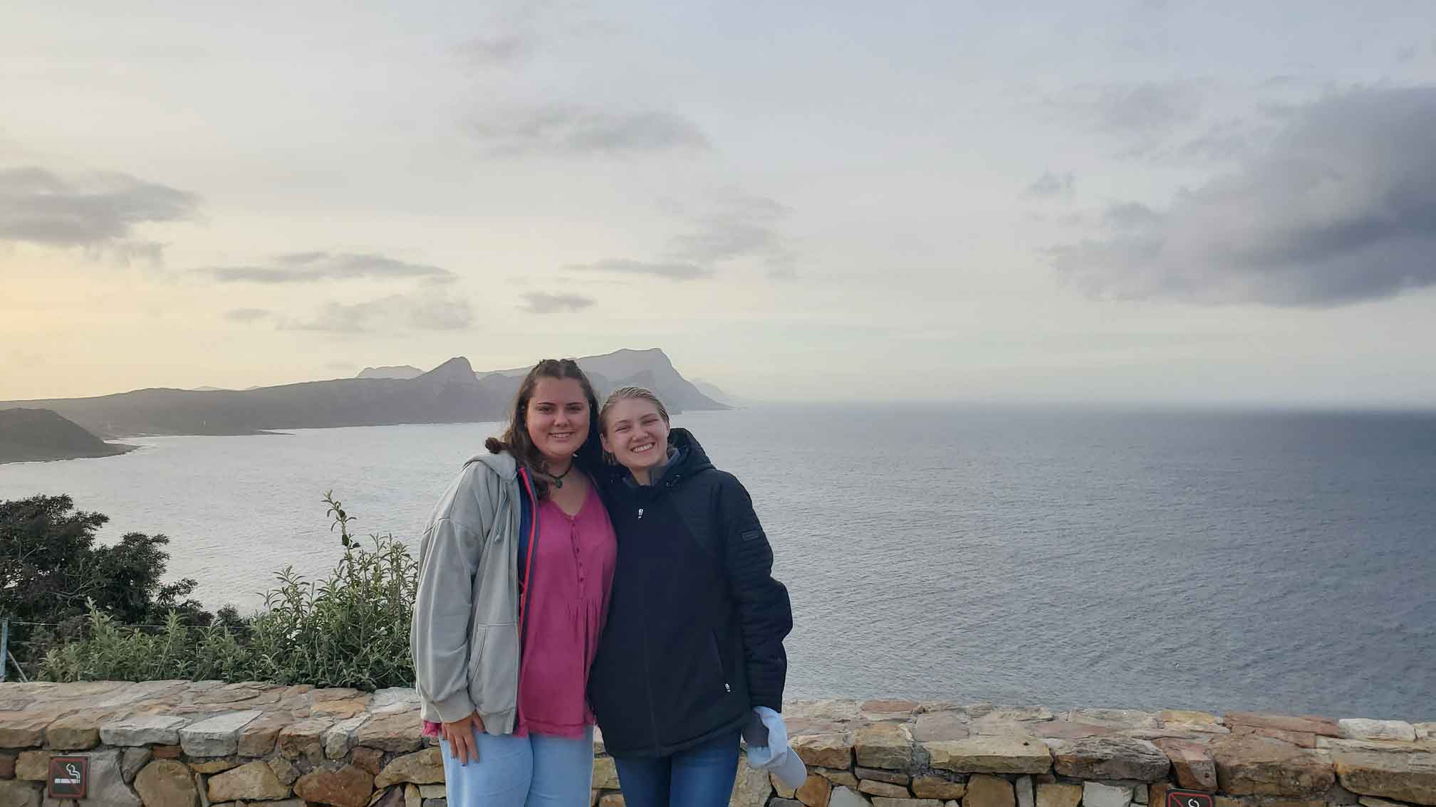 Two girls smiling in front of the sea