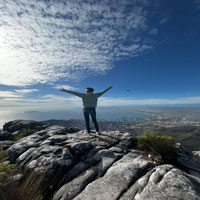 Man posing on mountain with back turned to camera