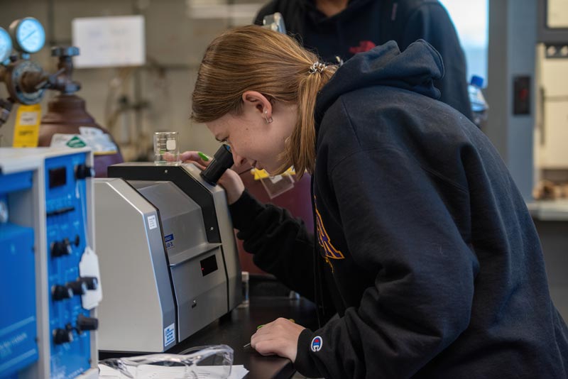 chemistry student peering through microscope