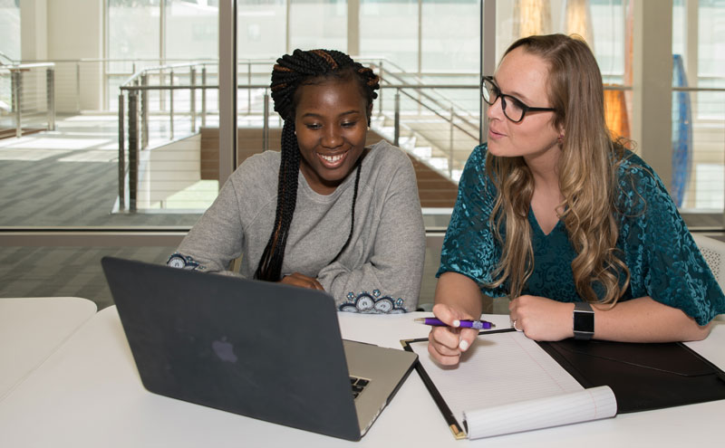 3 women chatting at a table with tablets in front of them